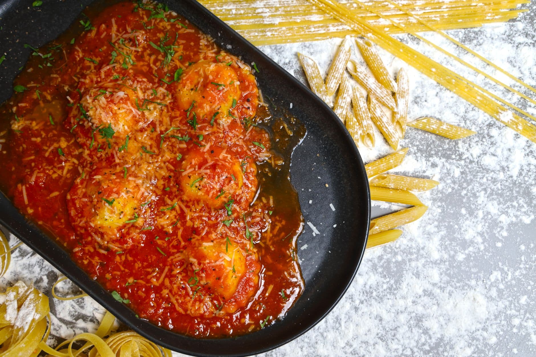 A mouthwatering homemade Italian dish with tomato sauce and herbs in a black pan.