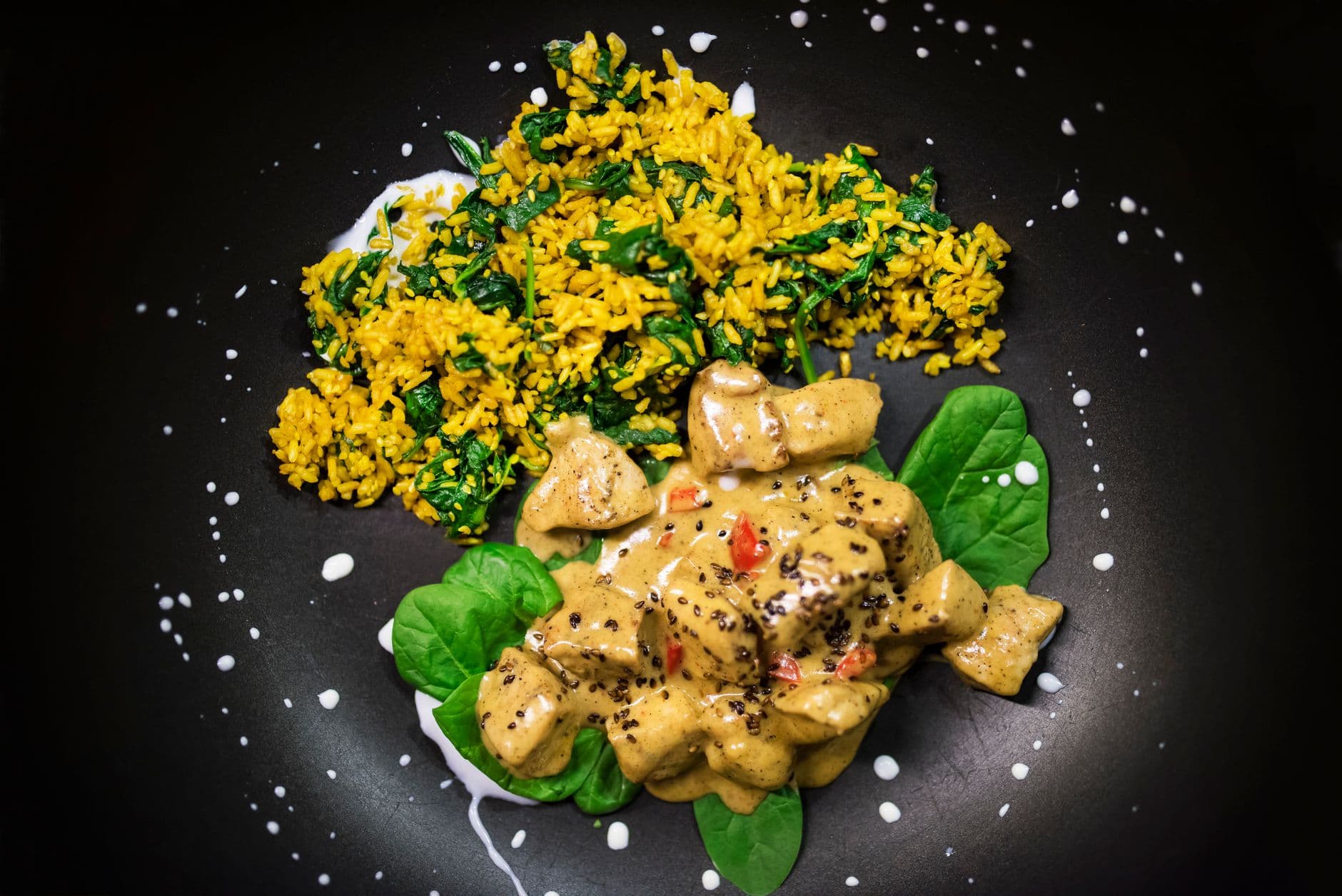 A vibrant plate of Indian chicken curry with rice, garnished with lime and fresh herbs.
