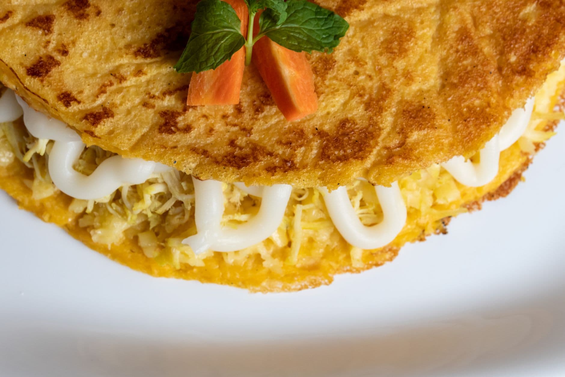 A delectable cheese-filled omelette garnished with fresh mint and carrot slices.
